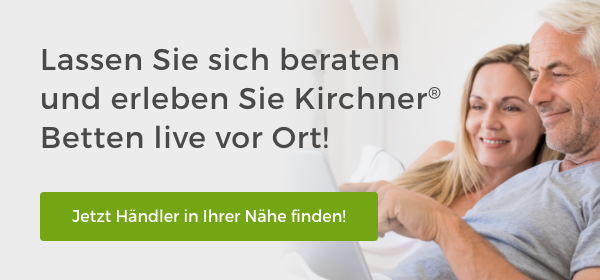 Besser schlafen in Kirchner Betten. Ein älteres Paar liegt im Bett und schaut in ein Tablet.