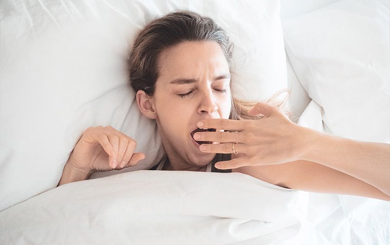 EIne Person liegt gähnend im Bett